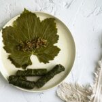Close-up of homemade dolma yalanji with grape leaves on a textured plate.